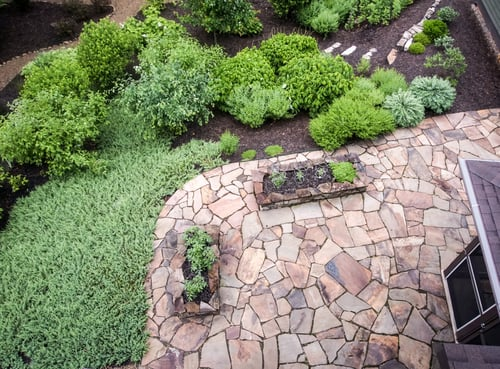 Flagstone patio surrounded by planted beds and groundcover
